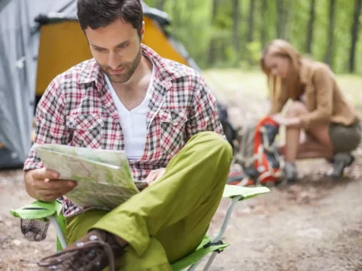Mann verwendet Karte und möchte einen Campingplatz finden.